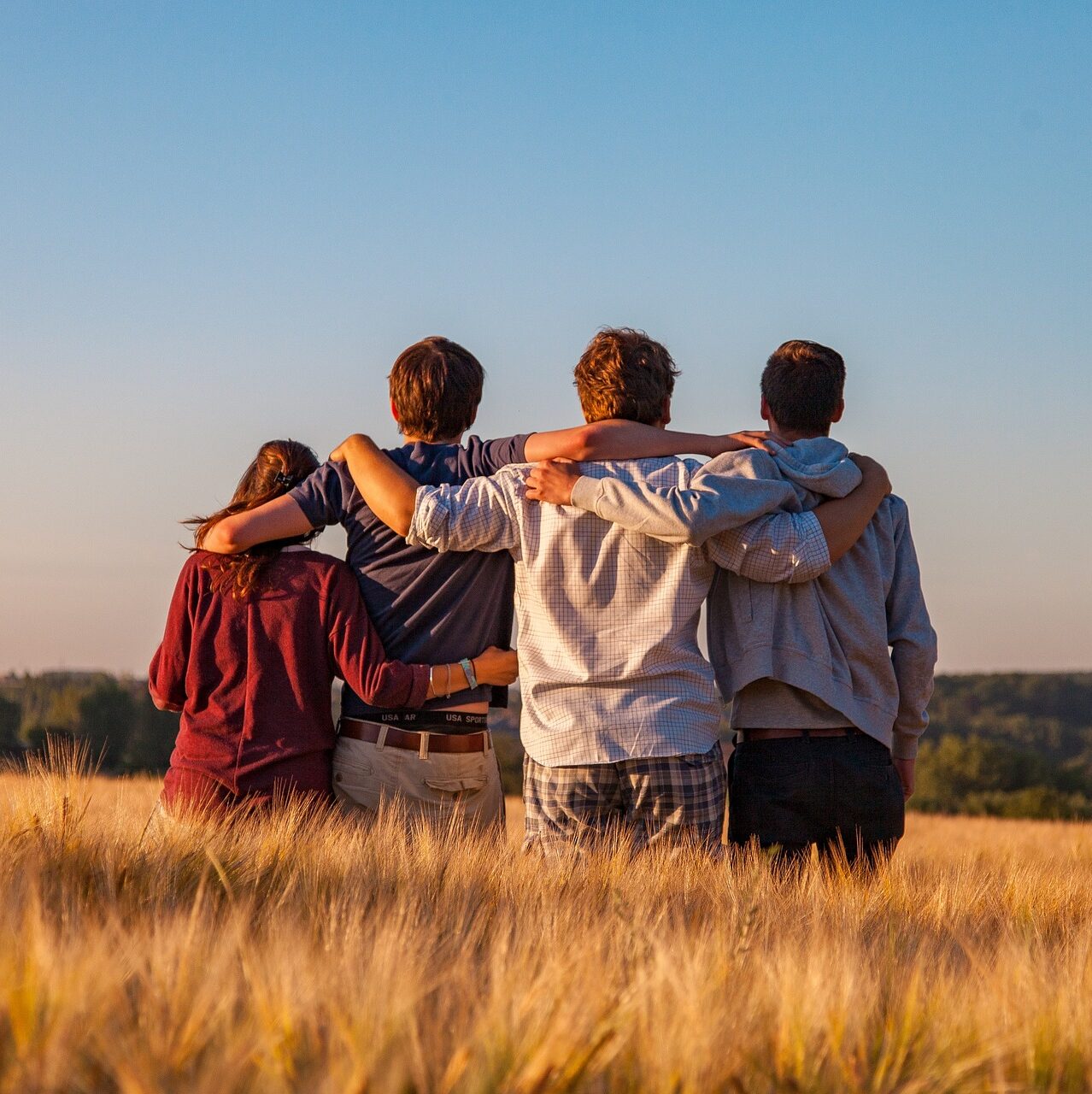 eine Gruppe von vier Jugendlichen steht auf einem Feld